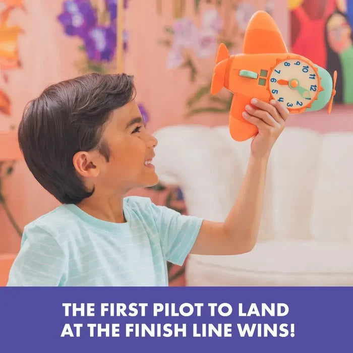 A child plays with an orange airplane toy that features a colorful analog clock face on its side.