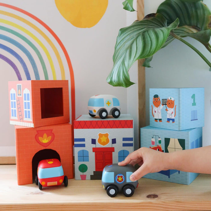 Colorful stacking cubes with building graphics and matching wooden toy cars on a wooden surface.