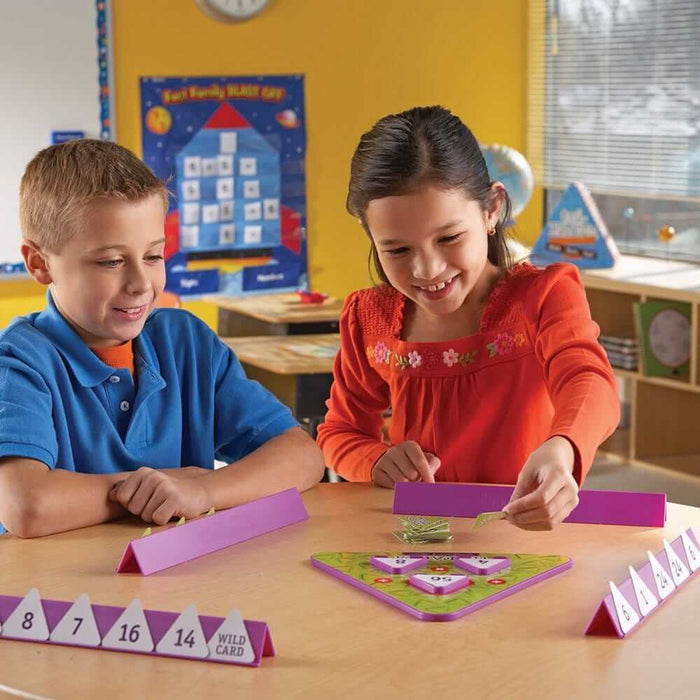 Two children play a math game with a green triangular board and numbered triangle cards in purple stands.