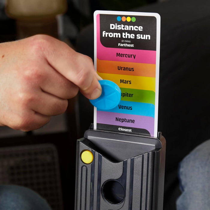 Hand places a blue disc on a colorful planetary trivia card held in a black plastic tower with a yellow button.