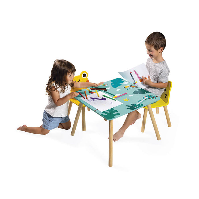 Two children drawing at a teal tropical-patterned wooden table with two yellow animal-shaped chairs.