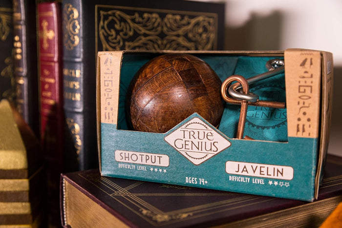 Teal box with a dark wooden sphere and metal ring puzzles sitting on a stack of vintage leather-bound books.