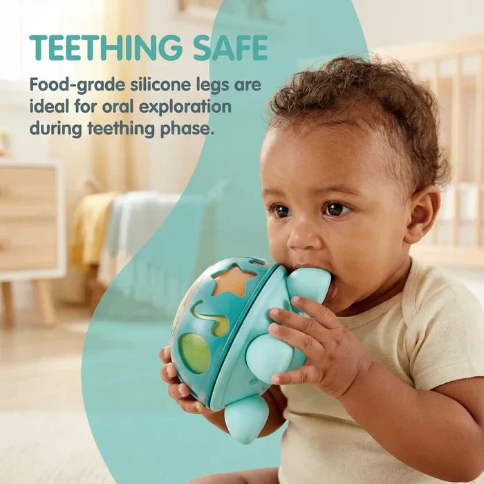 Baby biting on the soft silicone leg of a teal turtle toy with star and music note shape cutouts.