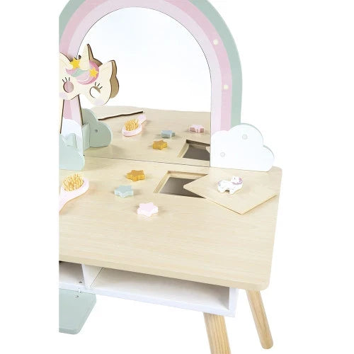 Pastel wooden vanity with rainbow mirror, unicorn mask, star accessories, and hairbrush on a light wood tabletop.