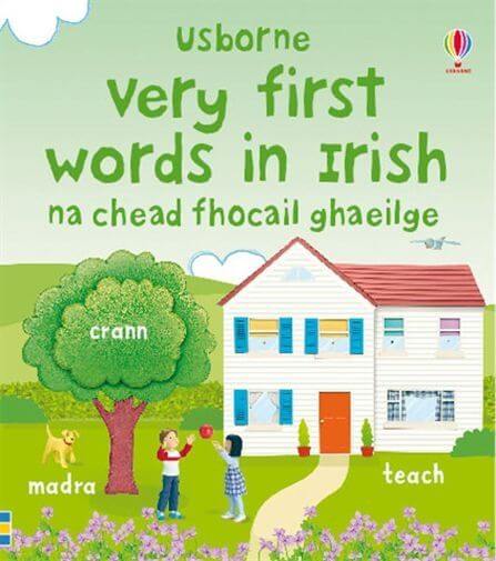 Green book cover with a white house, large tree, and children on a lawn, labeled with Irish vocabulary.