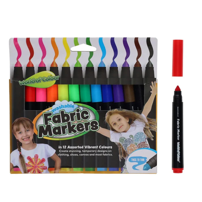 12 vibrant fabric markers in a box featuring kids in decorated shirts, with one loose red marker uncapped.