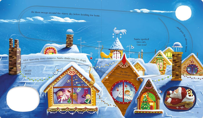 Illustrated book page of a snowy village at night with a grooved track and a small 3D wind-up Santa in a red sleigh.