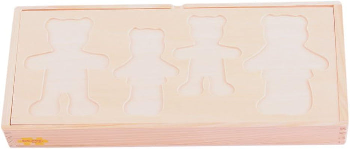 Light wood storage box with four bear-shaped family cutouts on the lid for a children's dress-up puzzle.