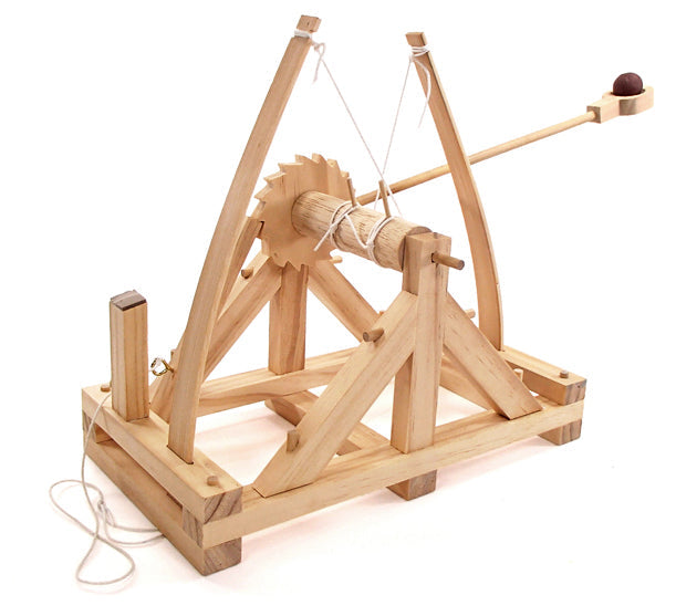 Light wood toy catapult featuring a throwing arm with a brown ball, a ratchet gear, and white tension strings.