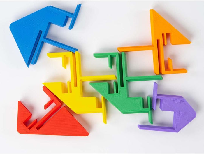 Six colorful, geometric plastic puzzle pieces with notches and tabs scattered on a white surface.