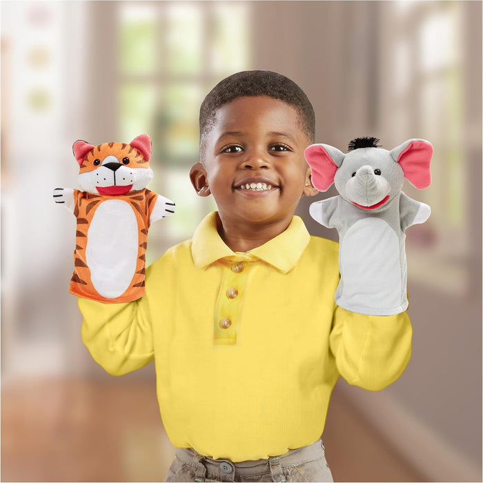 Young boy wearing an orange tiger hand puppet and a gray elephant hand puppet with pink ears.